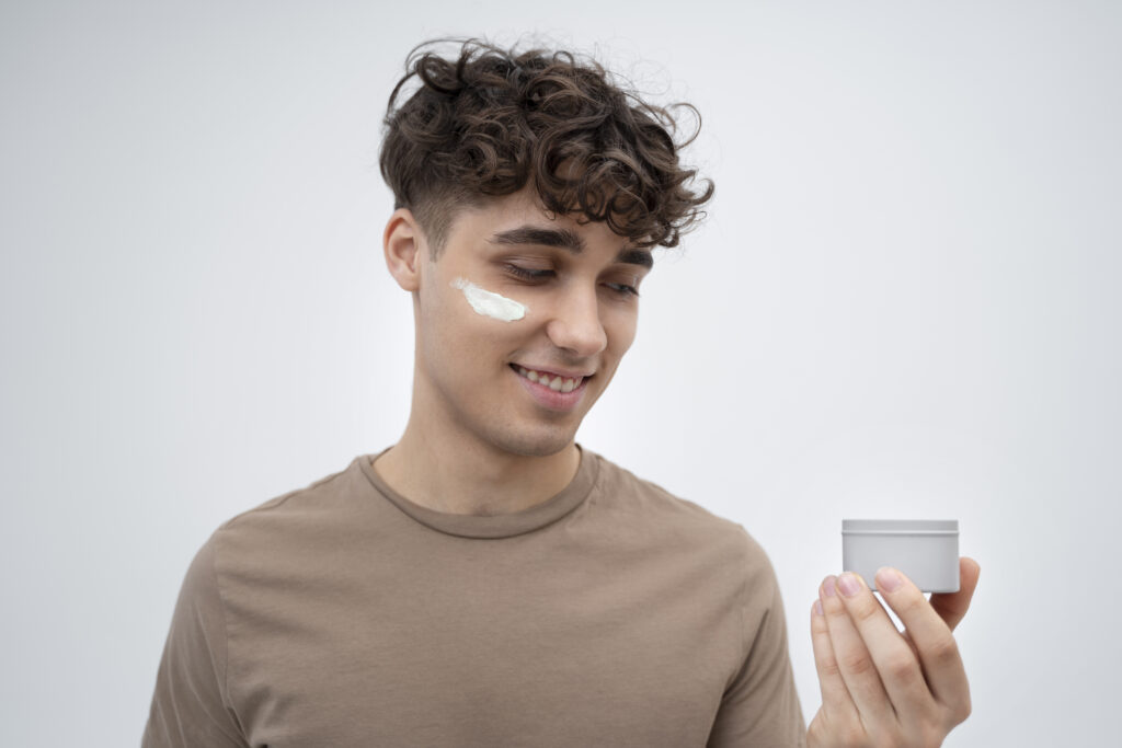 young man moisturizing his face